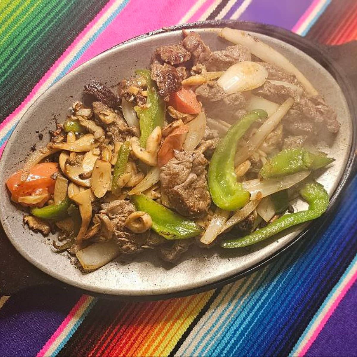Fajita Trio — grilled steak, chicken and shrimp with onion, mushroom, green pepper and tomato on a skillet at Mexican Fiesta 2 in Canton